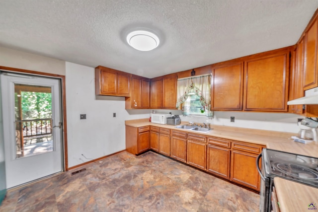 kitchen featuring a sink, baseboards, brown cabinetry, and a textured ceiling