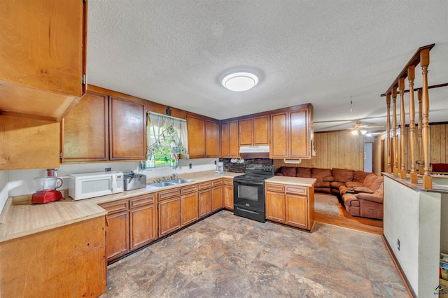 kitchen featuring brown cabinets, light countertops, black electric range, open floor plan, and white microwave