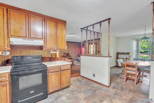 kitchen with wooden walls, brown cabinets, open floor plan, black / electric stove, and under cabinet range hood