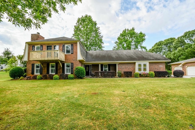 colonial-style house with brick siding, a chimney, a balcony, and a front yard