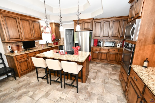 kitchen with stone finish floor, a kitchen bar, appliances with stainless steel finishes, tasteful backsplash, and a center island