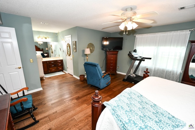 bedroom with a textured ceiling, a ceiling fan, baseboards, visible vents, and dark wood-style floors