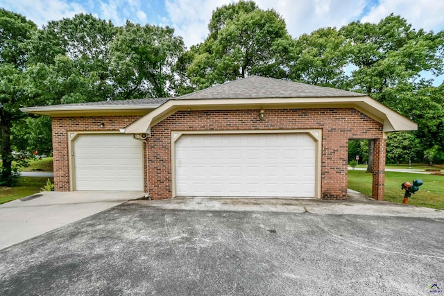 view of front of property featuring roof with shingles, a front lawn, brick siding, a garage, and driveway