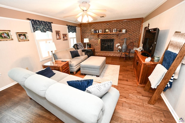living room featuring a ceiling fan, a fireplace, wood finished floors, baseboards, and ornamental molding