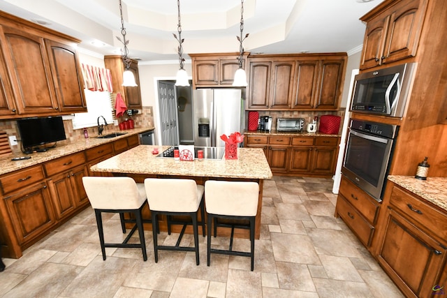 kitchen with decorative backsplash, a kitchen breakfast bar, crown molding, appliances with stainless steel finishes, and a sink