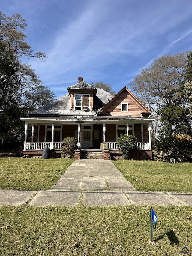 country-style home with a front lawn, covered porch, and a chimney