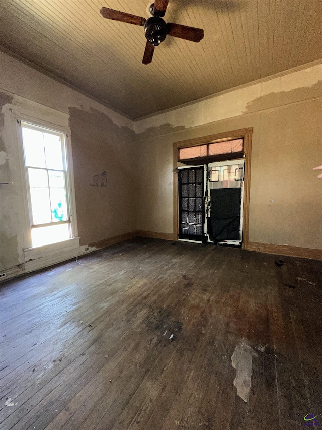 unfurnished room featuring ceiling fan, dark wood finished floors, wooden ceiling, and plenty of natural light