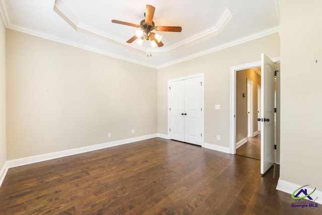 unfurnished room with crown molding, a raised ceiling, ceiling fan, and dark wood finished floors