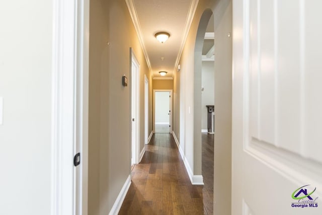 hall with arched walkways, baseboards, dark wood finished floors, and ornamental molding