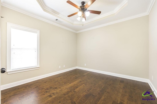 empty room with a ceiling fan, visible vents, crown molding, a tray ceiling, and dark wood-type flooring