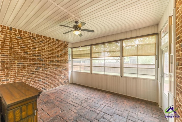 unfurnished sunroom featuring a ceiling fan and a wealth of natural light