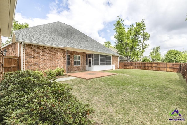 back of property with a shingled roof, brick siding, a fenced backyard, a patio area, and a yard