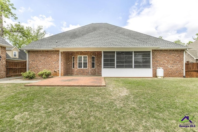 rear view of house featuring a yard, a patio, fence, and a shingled roof