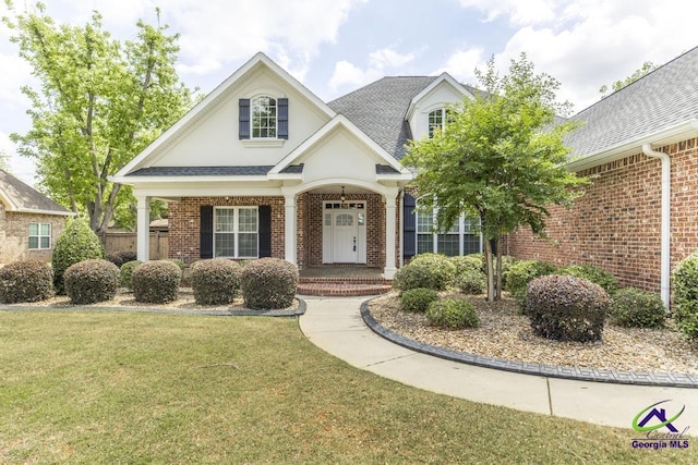 view of front of home with a porch, brick siding, and a front lawn