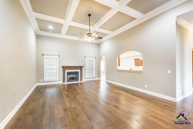 unfurnished living room with arched walkways, ceiling fan, coffered ceiling, and beam ceiling