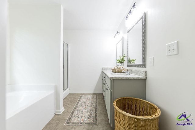 bathroom featuring vanity, tile patterned floors, baseboards, a garden tub, and a stall shower
