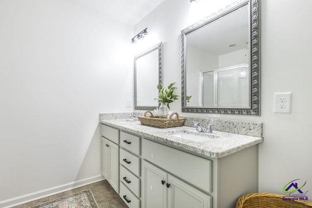 full bath featuring double vanity, a sink, baseboards, and a shower stall