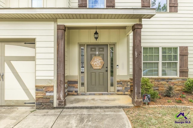 entrance to property with board and batten siding, stone siding, and a garage