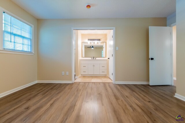 133 Avalon Dr, Warner Robins, GA 31093 - unfurnished bedroom featuring a sink, baseboards, ensuite bath, and light wood-style flooring