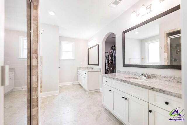 full bath featuring a walk in closet, a sink, two vanities, a shower stall, and visible vents