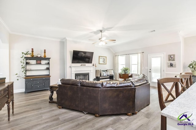 living room with crown molding, visible vents, a fireplace, ceiling fan, and light wood finished floors