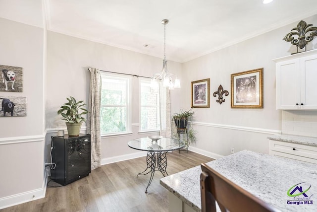 dining room featuring crown molding, baseboards, a notable chandelier, and light wood-style floors