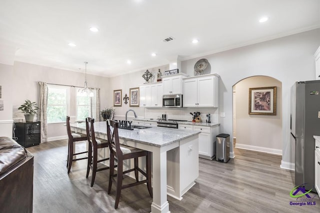 kitchen featuring stainless steel appliances, baseboards, white cabinetry, and a sink