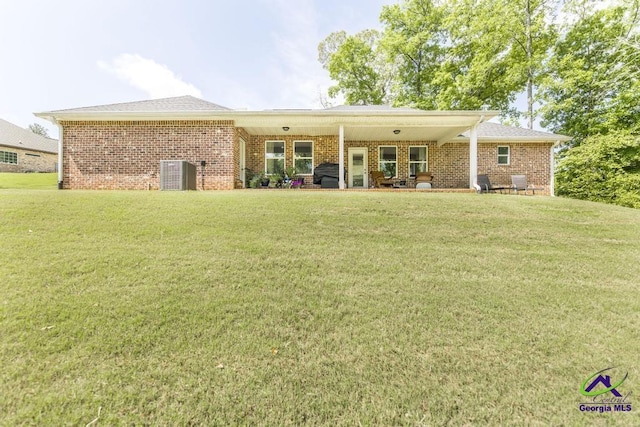 back of house with brick siding, a lawn, and central air condition unit
