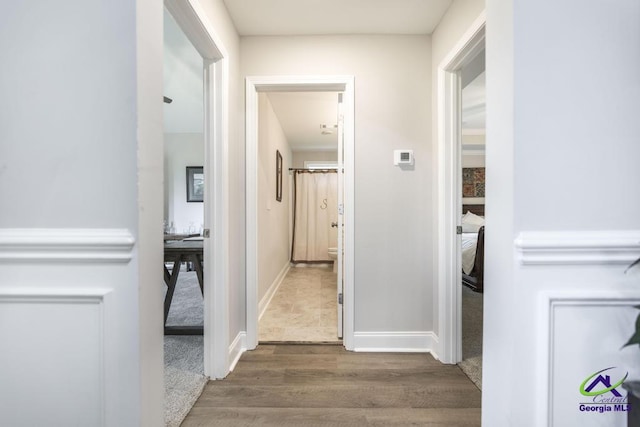 hallway featuring baseboards and wood finished floors