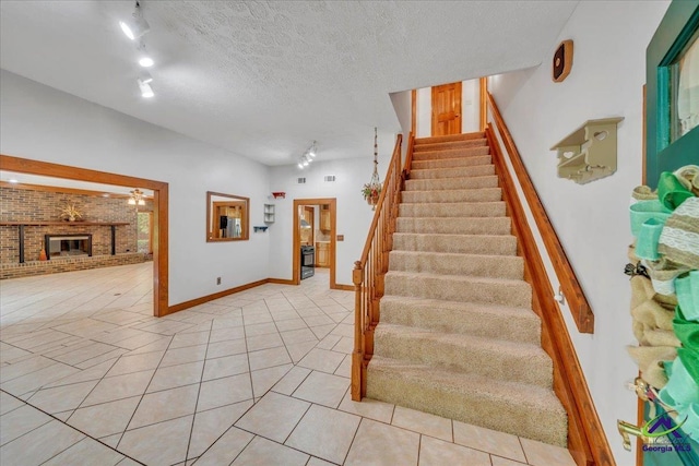 124 Joy Dr, Warner Robins, GA 31088 - stairway featuring track lighting, tile patterned flooring, a brick fireplace, a textured ceiling, and baseboards