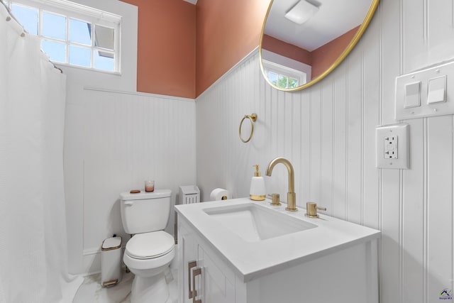 bathroom featuring vanity, plenty of natural light, a decorative wall, and toilet