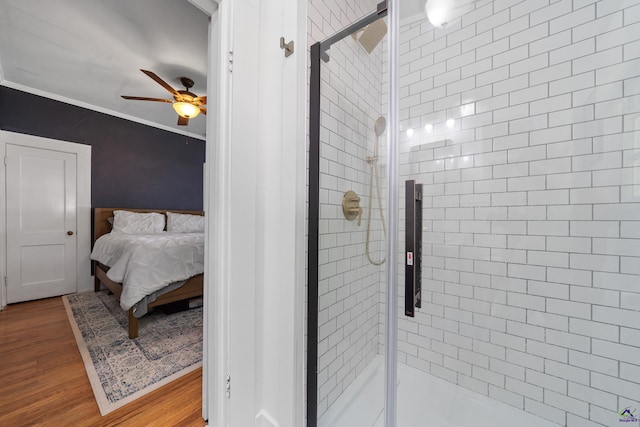 ensuite bathroom featuring ornamental molding, wood finished floors, connected bathroom, a shower stall, and a ceiling fan