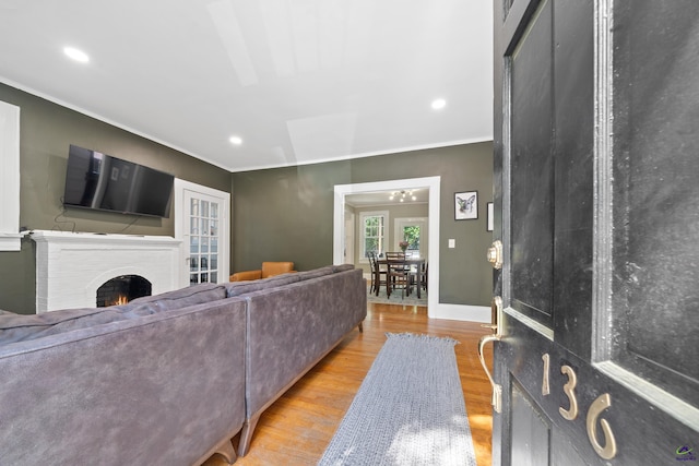 living area featuring a fireplace, wood finished floors, baseboards, ornamental molding, and recessed lighting