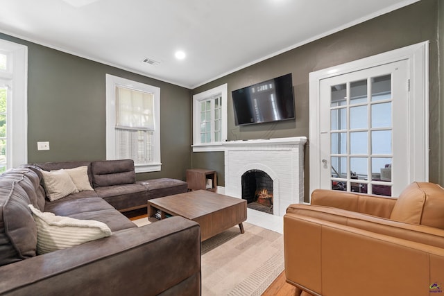 living room featuring a fireplace, light wood-style flooring, recessed lighting, visible vents, and ornamental molding