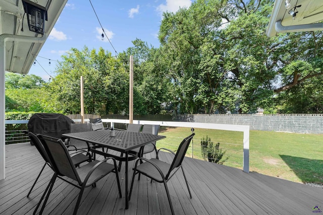 wooden deck featuring outdoor dining area, a fenced backyard, grilling area, and a yard