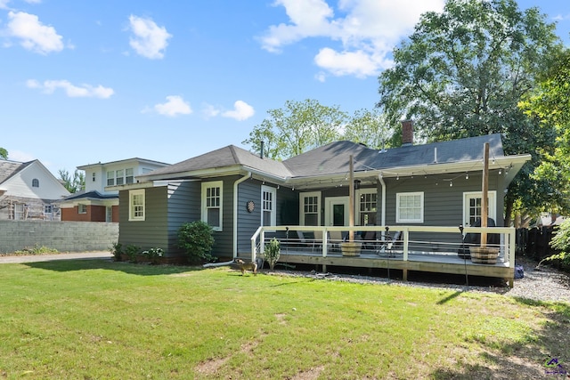 rear view of property with a lawn, a wooden deck, fence, and a chimney