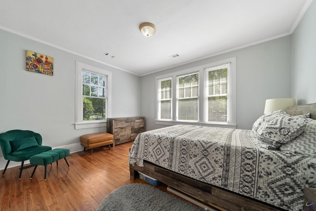 bedroom with crown molding, baseboards, and wood finished floors