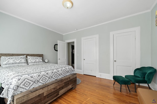 bedroom featuring baseboards, ornamental molding, and wood finished floors