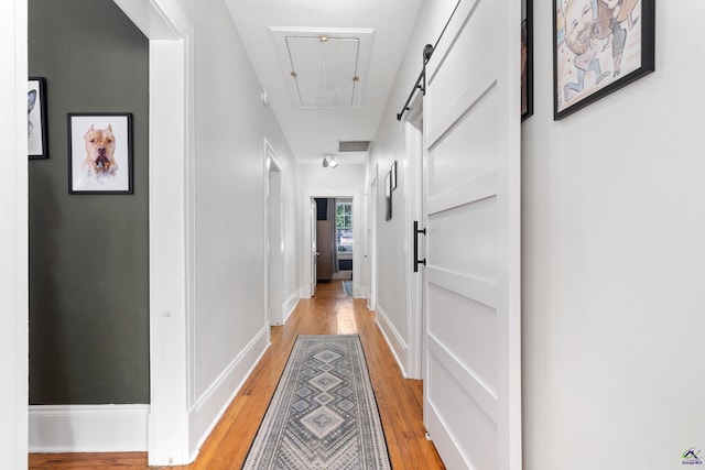 hallway featuring visible vents, attic access, and light wood finished floors
