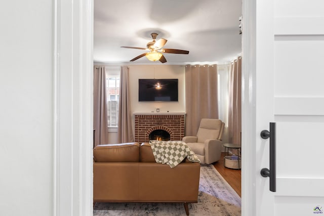 sitting room with ceiling fan, wood finished floors, and a fireplace