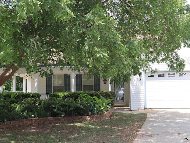 view of property hidden behind natural elements with an attached garage and driveway