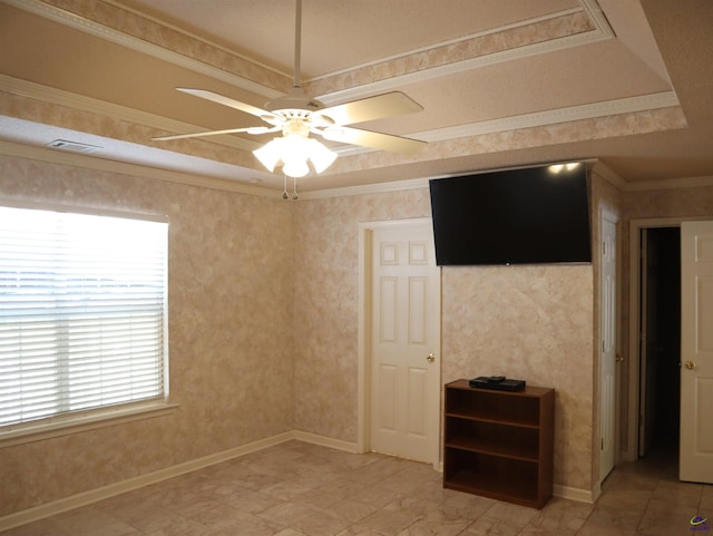 spare room featuring crown molding, a ceiling fan, a wealth of natural light, and a raised ceiling