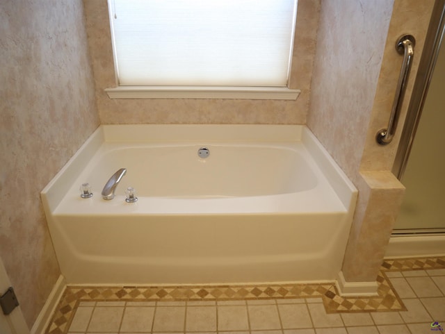bathroom featuring plenty of natural light, a garden tub, and tile patterned floors