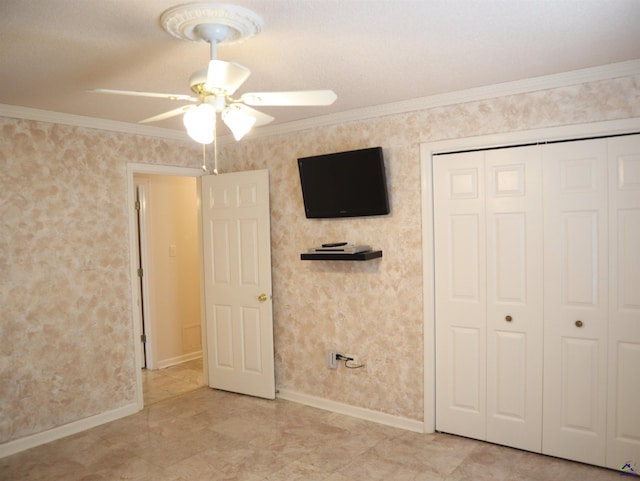 unfurnished bedroom featuring baseboards, ornamental molding, a ceiling fan, and a closet