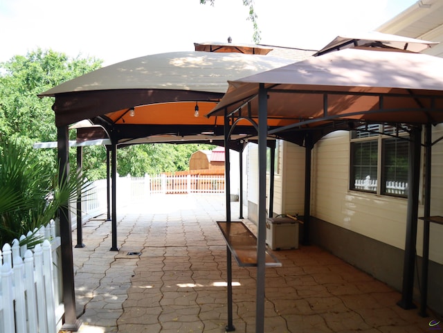 view of patio featuring a gazebo, fence, an outbuilding, and a storage unit