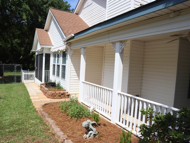 view of property exterior with covered porch, fence, a shingled roof, and a sunroom