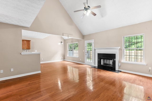 203 York Ln, Macon, GA 31220 - unfurnished living room featuring wood finished floors, baseboards, high vaulted ceiling, a fireplace with raised hearth, and a ceiling fan