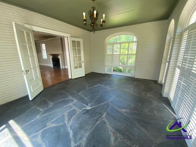 1218 Nottingham Dr, Macon, GA 31210 - unfurnished dining area with stone floors, french doors, and a chandelier