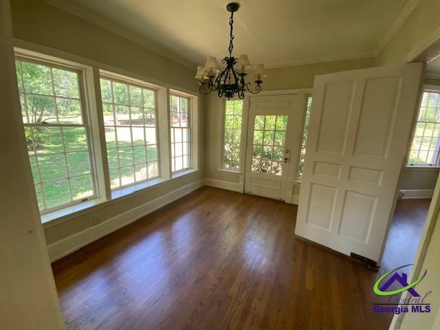 1218 Nottingham Dr, Macon, GA 31210 - unfurnished dining area with baseboards, ornamental molding, a notable chandelier, and dark wood-style floors