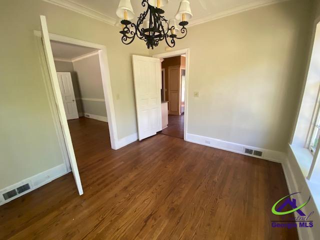 1218 Nottingham Dr, Macon, GA 31210 - unfurnished dining area with visible vents, crown molding, baseboards, dark wood-style floors, and a notable chandelier